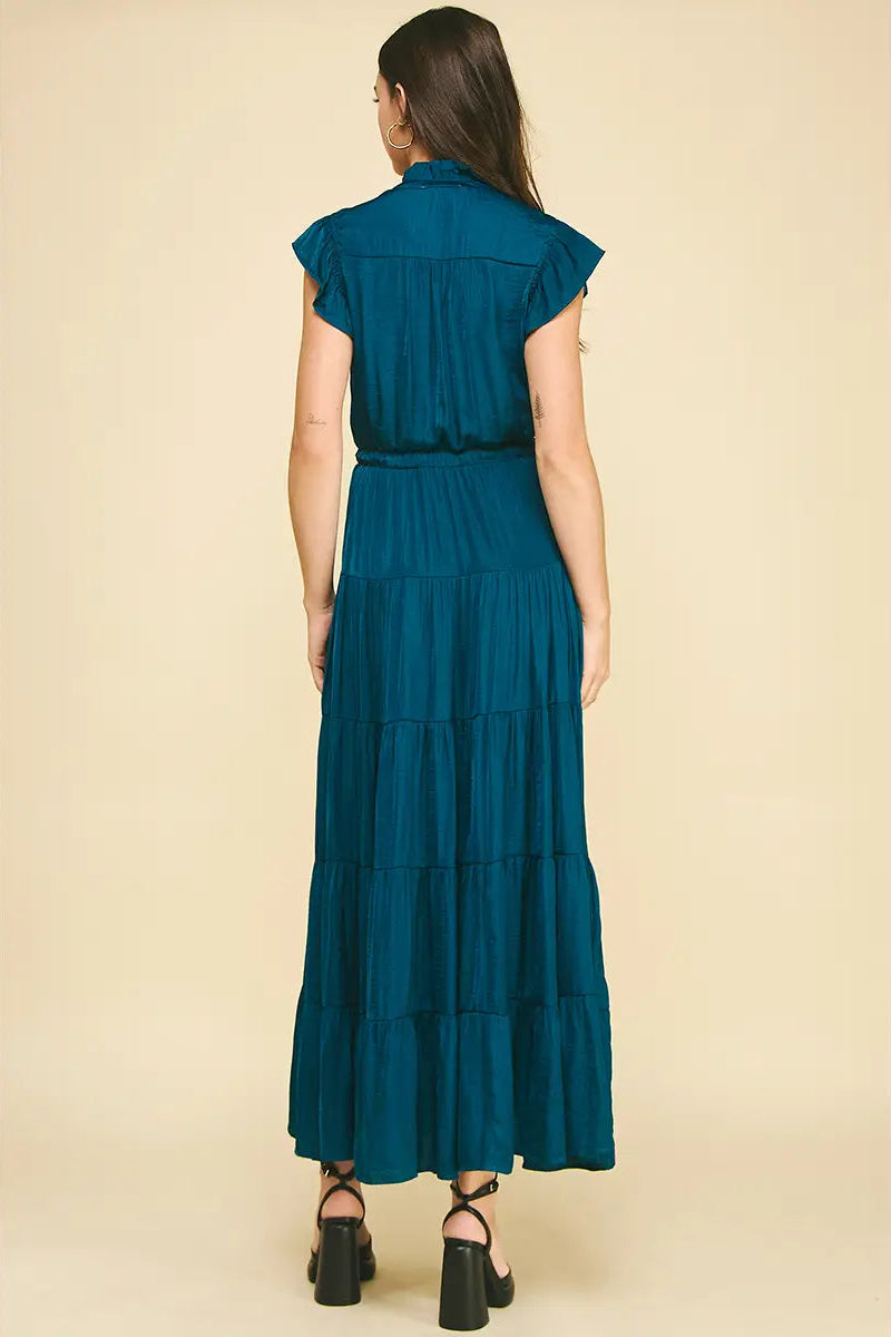 Woman wearing a teal dress against a beige background